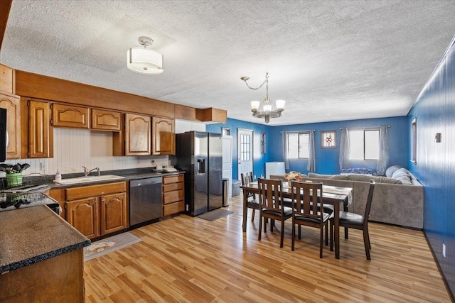 kitchen with an inviting chandelier, sink, appliances with stainless steel finishes, decorative light fixtures, and light hardwood / wood-style floors