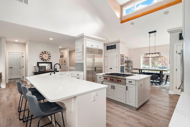 kitchen featuring a center island, high vaulted ceiling, hanging light fixtures, appliances with stainless steel finishes, and white cabinetry