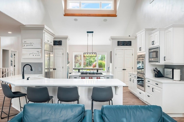 kitchen with decorative backsplash, sink, pendant lighting, built in appliances, and white cabinetry