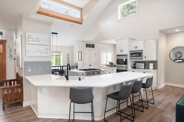 kitchen with a kitchen bar, kitchen peninsula, high vaulted ceiling, and appliances with stainless steel finishes