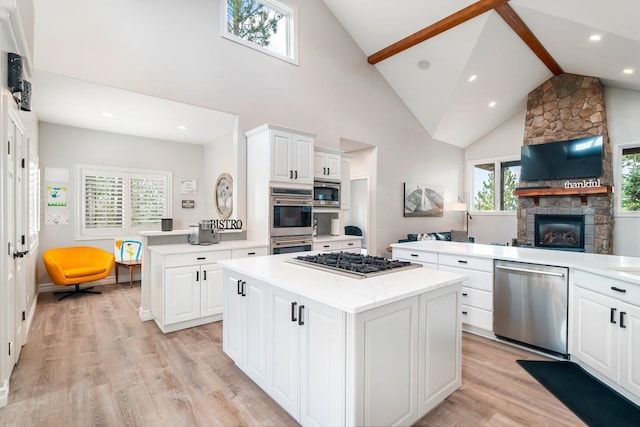 kitchen with white cabinets, light wood-type flooring, appliances with stainless steel finishes, a kitchen island, and kitchen peninsula