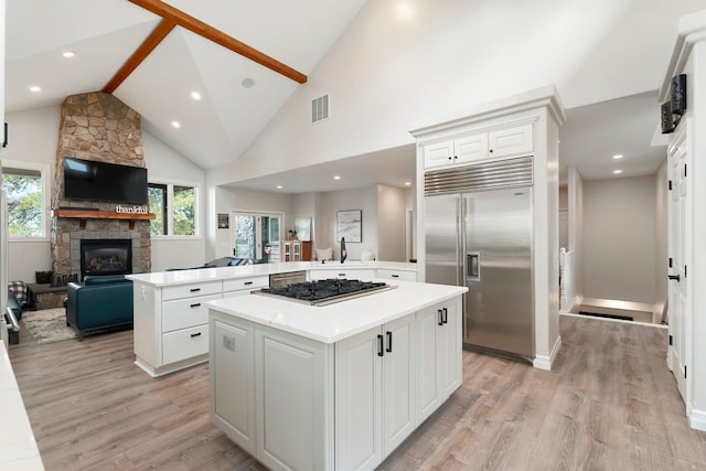 kitchen featuring white cabinets, appliances with stainless steel finishes, plenty of natural light, a kitchen island, and kitchen peninsula