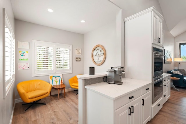 interior space with white cabinets, light wood-type flooring, double oven, and light stone countertops