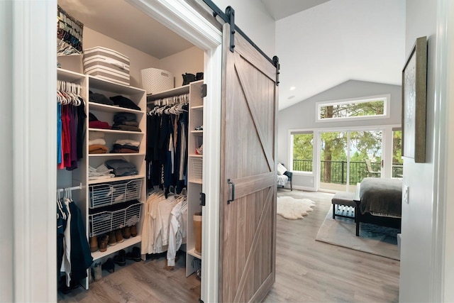 walk in closet featuring hardwood / wood-style floors, a barn door, and vaulted ceiling