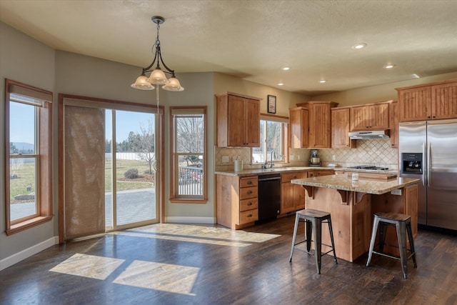 kitchen with hanging light fixtures, stainless steel appliances, dark hardwood / wood-style floors, backsplash, and a kitchen island