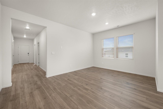 spare room with a textured ceiling and light hardwood / wood-style flooring