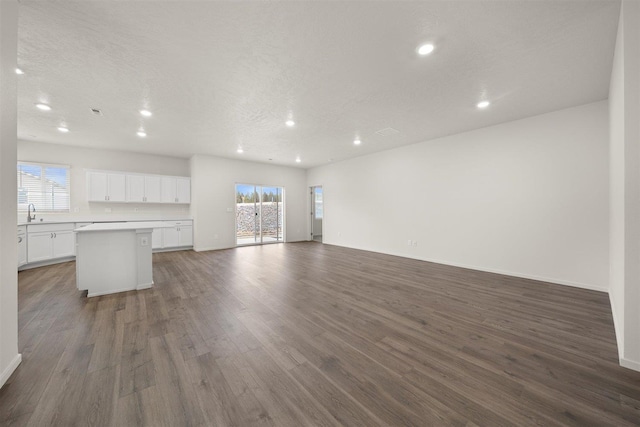 unfurnished living room with a textured ceiling and dark hardwood / wood-style flooring