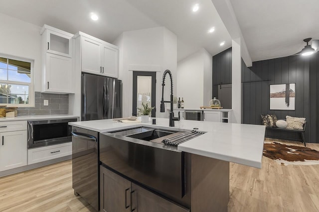 kitchen featuring stainless steel appliances, white cabinetry, a center island with sink, and light hardwood / wood-style flooring