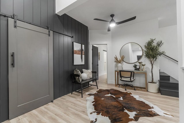 foyer entrance featuring light wood-type flooring, a barn door, and ceiling fan