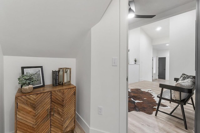 hallway with light hardwood / wood-style floors and lofted ceiling