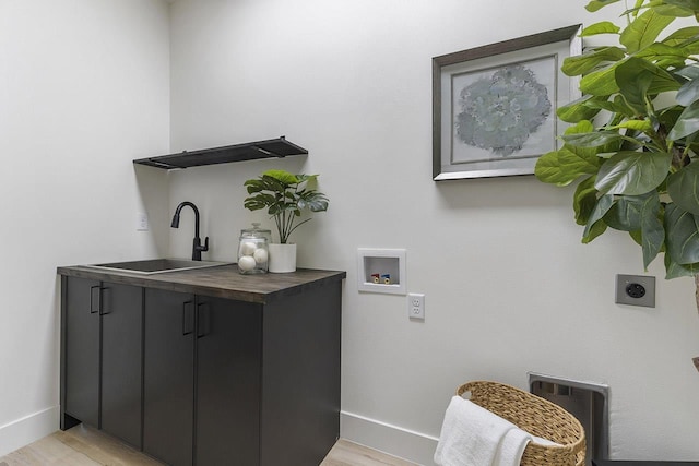 laundry room featuring hookup for an electric dryer, hookup for a washing machine, cabinets, sink, and light hardwood / wood-style flooring