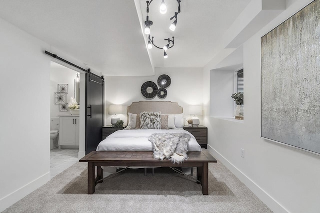 bedroom with a barn door, light colored carpet, and connected bathroom