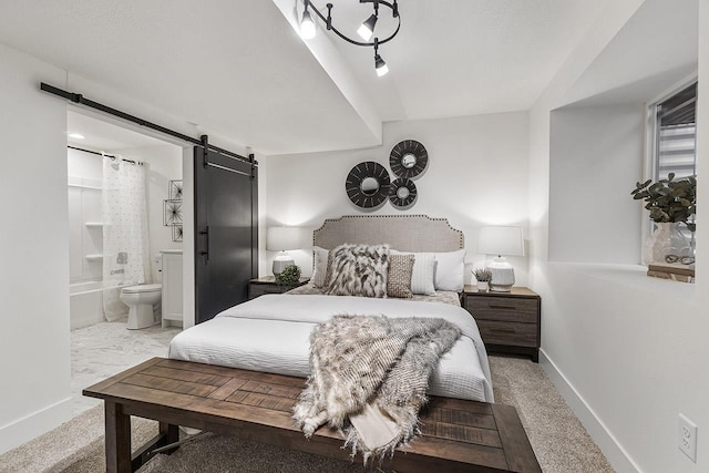 bedroom with light carpet, a barn door, and connected bathroom