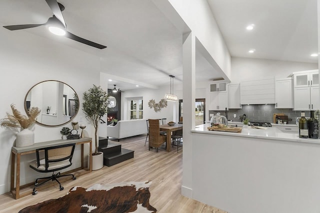 kitchen featuring white cabinetry, ceiling fan, tasteful backsplash, lofted ceiling, and light wood-type flooring