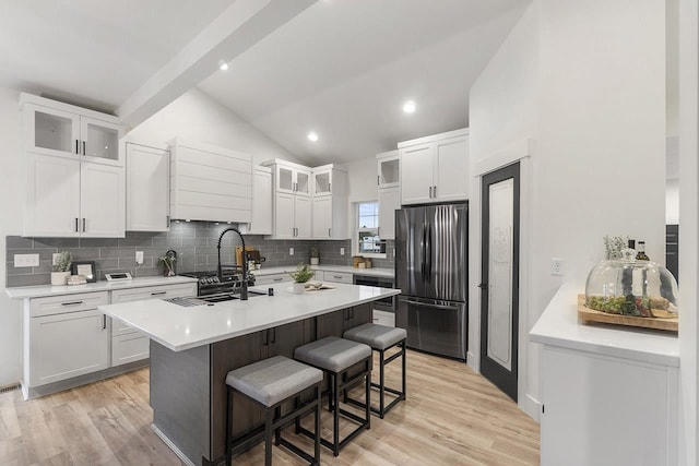 kitchen featuring stainless steel fridge, white cabinetry, lofted ceiling, and a breakfast bar area