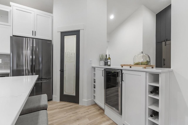 kitchen with stainless steel refrigerator, white cabinetry, wine cooler, and light wood-type flooring