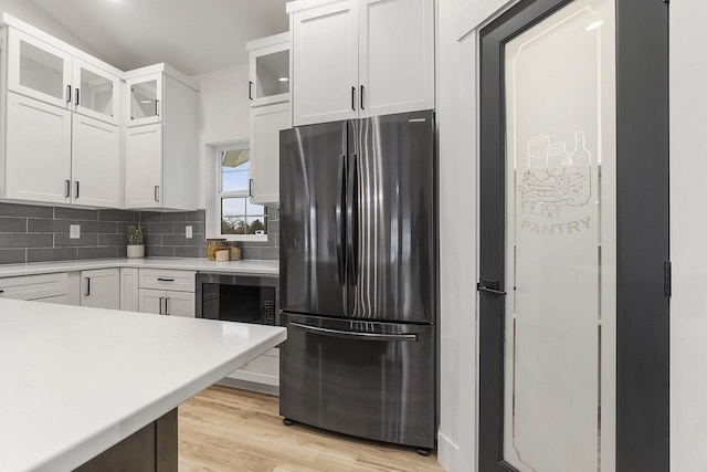 kitchen with white cabinetry, wine cooler, backsplash, stainless steel fridge, and light hardwood / wood-style floors