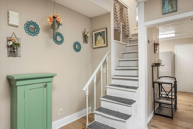 stairway with hardwood / wood-style floors and a textured ceiling