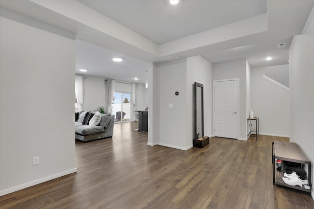 living room with a tray ceiling and dark wood-type flooring