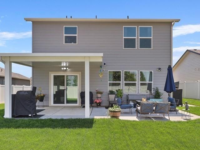 back of house featuring a lawn, a fire pit, and a patio area