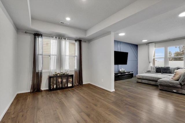 living room with dark hardwood / wood-style floors and a raised ceiling