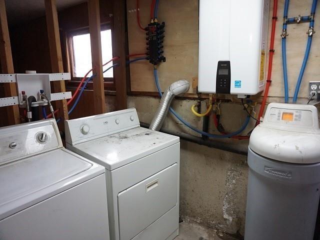 laundry room with tankless water heater and washing machine and clothes dryer