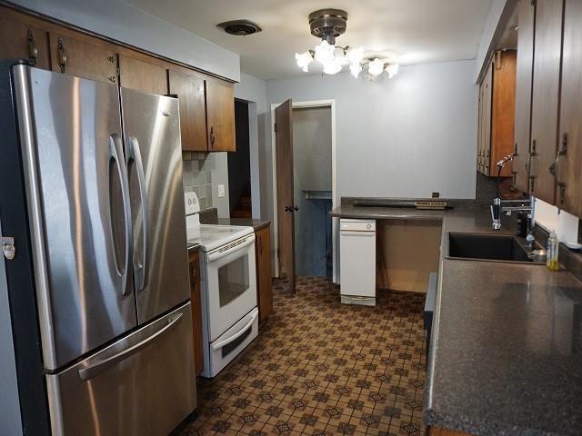 kitchen featuring backsplash, electric stove, sink, and stainless steel refrigerator