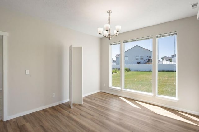 unfurnished dining area featuring hardwood / wood-style flooring and a notable chandelier