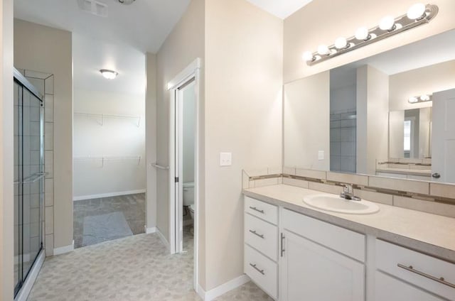 bathroom featuring an enclosed shower, vanity, and toilet