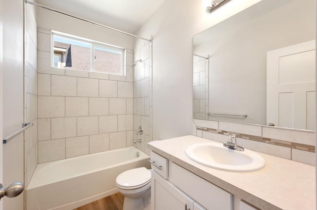 full bathroom featuring wood-type flooring, toilet, decorative backsplash, vanity, and tiled shower / bath