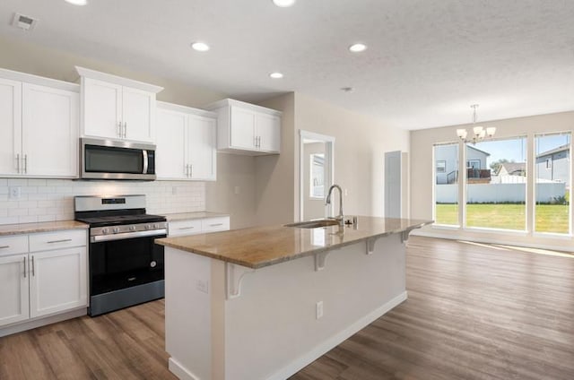 kitchen featuring white cabinets, appliances with stainless steel finishes, an island with sink, and sink