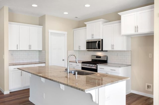 kitchen with appliances with stainless steel finishes, white cabinetry, a kitchen island with sink, and sink