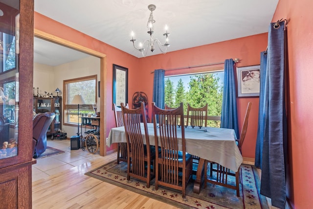 dining space with light hardwood / wood-style floors and an inviting chandelier