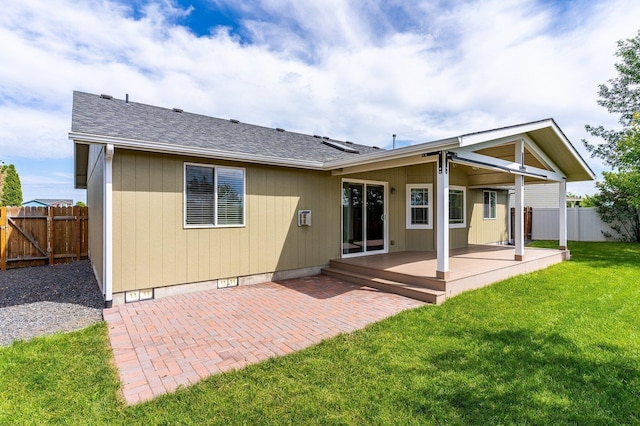 back of property featuring a wooden deck, a patio area, and a lawn