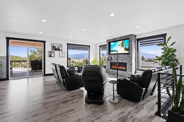 living room with hardwood / wood-style flooring, a stone fireplace, and plenty of natural light