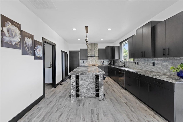 kitchen with tasteful backsplash, sink, wall chimney range hood, dishwasher, and a kitchen island