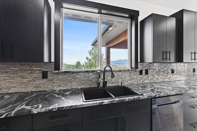 kitchen with tasteful backsplash, stainless steel dishwasher, dark stone countertops, and sink