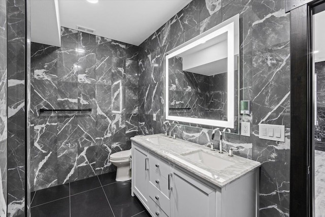 bathroom featuring tile patterned floors, vanity, toilet, and tile walls