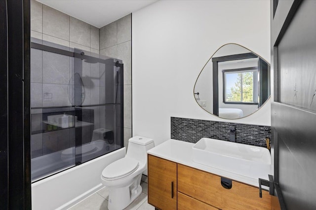 full bathroom featuring combined bath / shower with glass door, tile patterned floors, toilet, decorative backsplash, and vanity