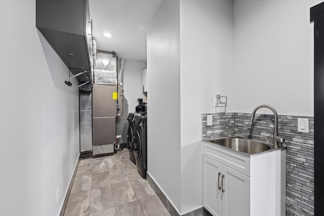 corridor featuring washing machine and clothes dryer, light tile patterned floors, heating unit, and sink