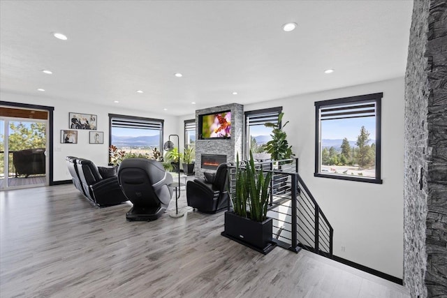 living room with a healthy amount of sunlight, a stone fireplace, and light hardwood / wood-style floors