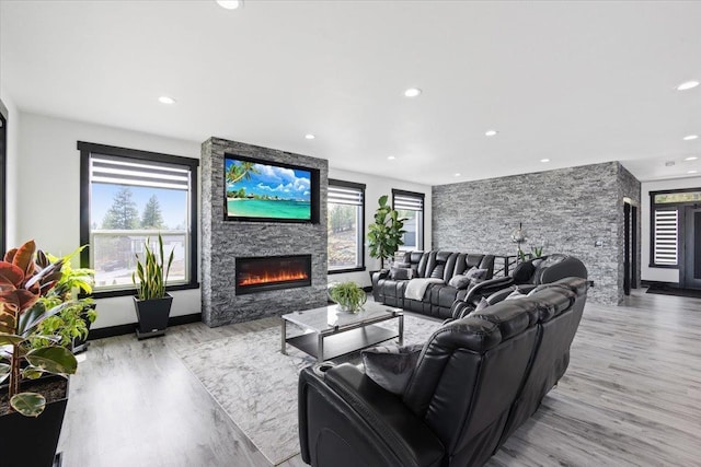 living room with a fireplace, a wealth of natural light, and light hardwood / wood-style flooring