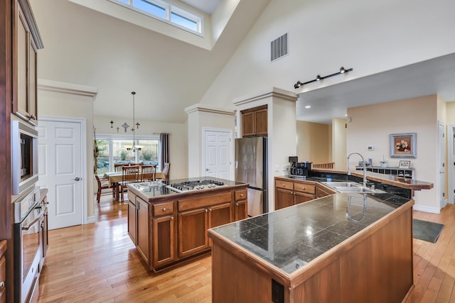 kitchen featuring sink, stainless steel appliances, high vaulted ceiling, pendant lighting, and a kitchen island