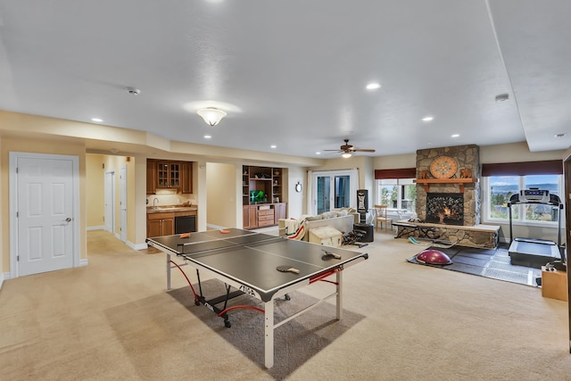 recreation room featuring ceiling fan, a fireplace, light colored carpet, and indoor wet bar