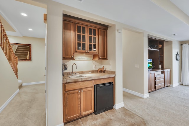 kitchen featuring tile countertops, sink, and light carpet