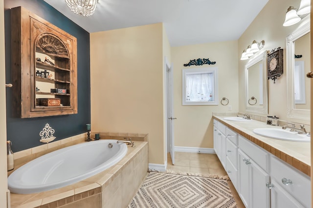 bathroom with tiled tub, tile patterned flooring, and vanity