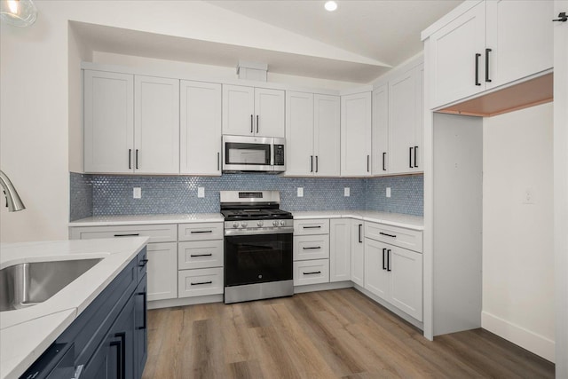4217 W Tolliver Ct, Spokane, WA 99208 - kitchen featuring appliances with stainless steel finishes, vaulted ceiling, light wood finished floors, backsplash, and recessed lighting