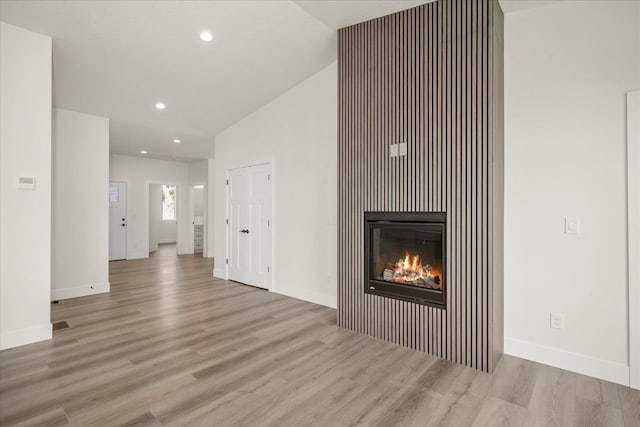 4217 W Tolliver Ct, Spokane, WA 99208 - unfurnished living room with lofted ceiling, wood finished floors, a glass covered fireplace, and recessed lighting