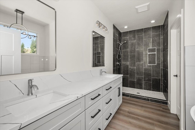 4217 W Tolliver Ct, Spokane, WA 99208 - bathroom with double vanity, a tile shower, recessed lighting, wood finished floors, and a textured ceiling