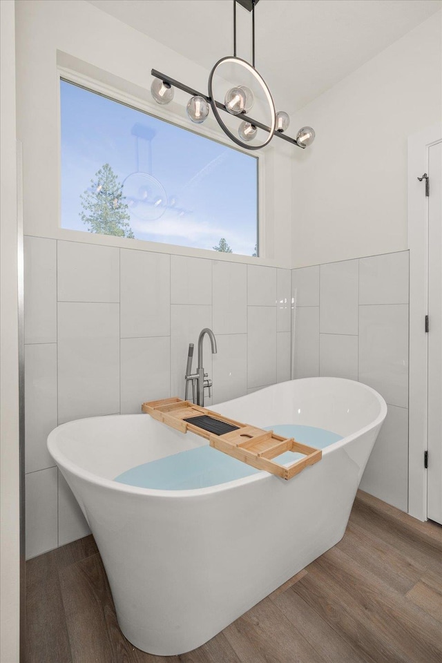 4217 W Tolliver Ct, Spokane, WA 99208 - bathroom with tile walls, wood finished floors, healthy amount of natural light, a freestanding tub, and a chandelier